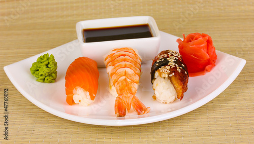 Photo: delicious sushi served on plate on bamboo mat delicious sushi served on plate on bamboo mat