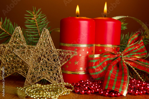 Photo: Two candles and christmas decorations, on brown background Two candles and christmas decorations, on brown background