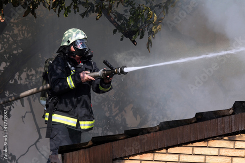 Photo: Fireman on the roof in a smoky environment Fireman on the roof in a smoky environment