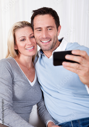 Photo: Couple photographing themselves on a mobile Couple photographing themselves on a mobile