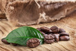 Coffee grains and green leaf on old wooden board