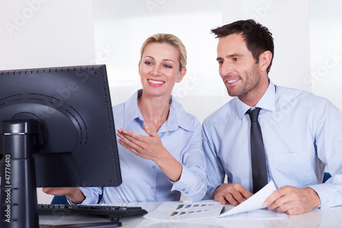 Photo: Smiling business colleagues discussing statistics Smiling business colleagues discussing statistics