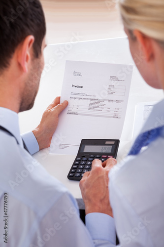 Photo: Colleagues checking an invoice on a calculator Colleagues checking an invoice on a calculator