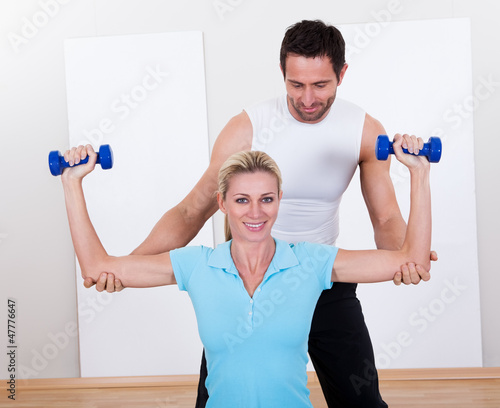 Photo: Fitness instructor helping a woman workout Fitness instructor helping a woman workout