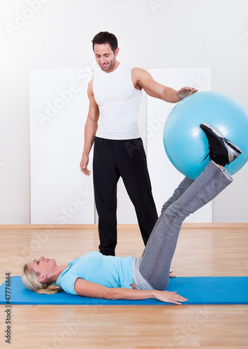 Photo: Instructor helping a woman with pilates exercises Instructor helping a woman with pilates exercises