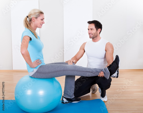 Photo: Instructor helping a woman with pilates exercises Instructor helping a woman with pilates exercises