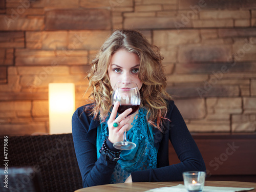 Photo: Beautiful Girl In Restaurant holding glass with red wine Beautiful Girl In Restaurant holding glass with red wine