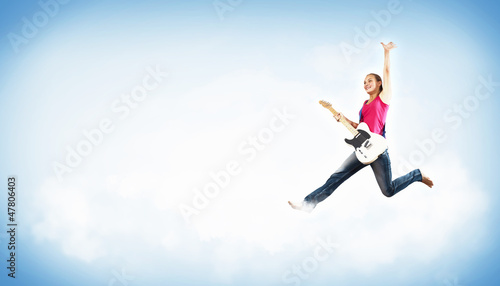 Photo: young woman playing on electro guitar and jumping young woman playing on electro guitar and jumping