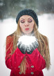 girl with cap and gloves playing with snow in the winter forest