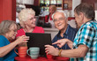 Seniors Having Fun with Computer in Cafe