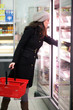 Photo: Frau steht im Supermarkt vor dem Kühlregal Frau steht im Supermarkt vor dem Kühlregal