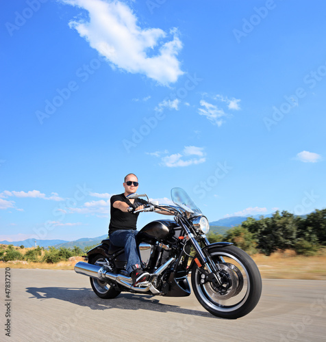 Photo: A biker riding a customized motorcycle on an open road A biker riding a customized motorcycle on an open road