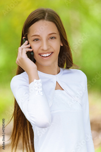 Photo: smiling teenage girl talking on mobile phone smiling teenage girl talking on mobile phone