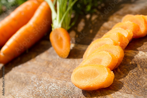 Photo: washed and fresh carrot on cutting board, outdoors washed and fresh carrot on cutting board, outdoors