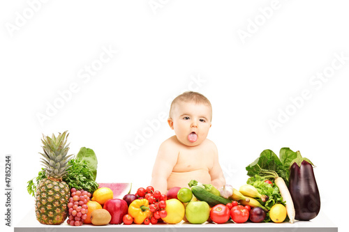Photo: Baby boy sitting on a table full of different fruits and vegetab Baby boy sitting on a table full of different fruits and vegetab