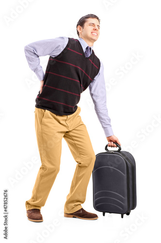 Photo: Man lifting his luggage and suffering from a back pain Man lifting his luggage and suffering from a back pain
