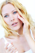 Portrait of beautiful woman applying moisturizer