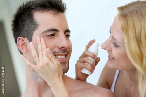 Photo: Woman applying sunscreen on her boyfriend's cheeks Woman applying sunscreen on her boyfriend's cheeks