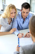 Cheerful couple signing property contract with real-estate agent