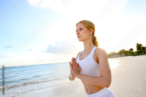 Photo: Beautiful woman doing yoga exercises by the beach Beautiful woman doing yoga exercises by the beach