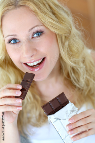 Photo: Blond woman eating chocolate bar Blond woman eating chocolate bar