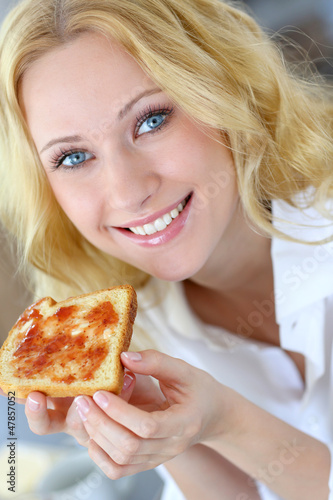 Photo: Beautiful girl eating toasted bread for breakfast Beautiful girl eating toasted bread for breakfast