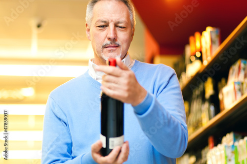 Photo: Man holding a bottle of red wine Man holding a bottle of red wine