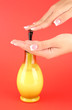 woman squeezing lotion on her hand, on red background close-up