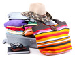 Closed silver suitcase with clothing isolated on white