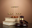 Golden scales of justice, gavel and books on brown background