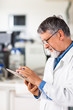 Senior doctor/scientist using his tablet computer at work