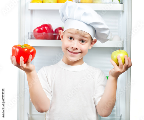Photo: cute smaster chef is choosing food near the open refrigerator cute smaster chef is choosing food near the open refrigerator