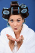 Woman with her hair in rollers blowing a kiss