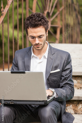 Photo: Young Businessman with Computer next to Swimming Pool Young Businessman with Computer next to Swimming Pool