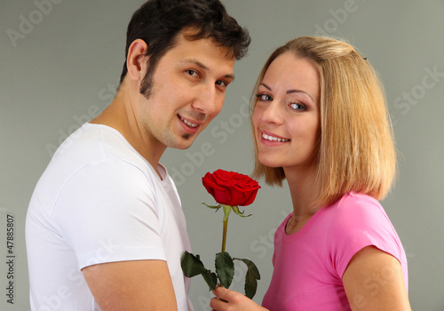 Photo: Loving couple with rose on grey background Loving couple with rose on grey background