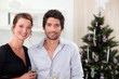 Couple posing in front of their Christmas tree