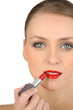 Young woman applying red lipstick