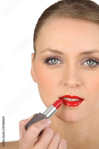 Photo: Young woman applying red lipstick Young woman applying red lipstick