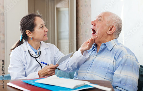 Photo: mature doctor looks the mouth of patient mature doctor looks the mouth of patient