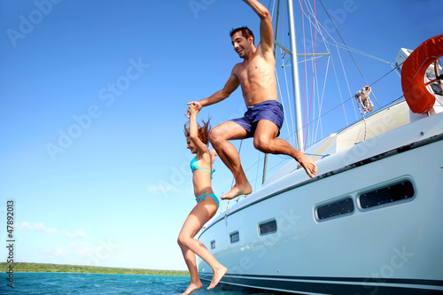 Photo: Young couple jumping in water from yacht Young couple jumping in water from yacht