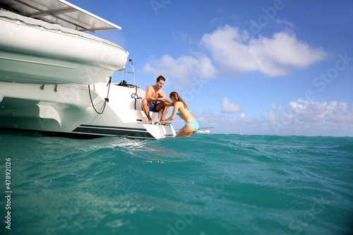 Photo: Young people swimming in the sea next to sailboat Young people swimming in the sea next to sailboat