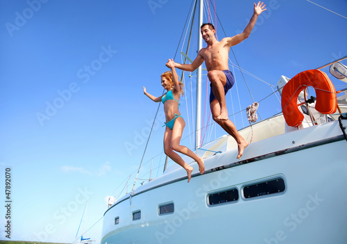 Photo: Young couple jumping in water from yacht Young couple jumping in water from yacht