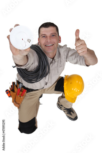 Photo: Tradesman holding up a smoke detector Tradesman holding up a smoke detector
