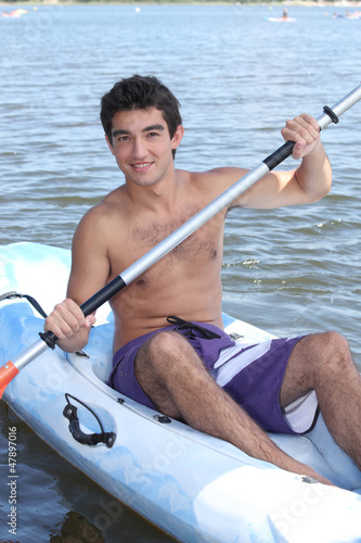 Photo: Boy paddling in canoe Boy paddling in canoe