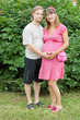 a happy pregnant woman with her husband rests in a park