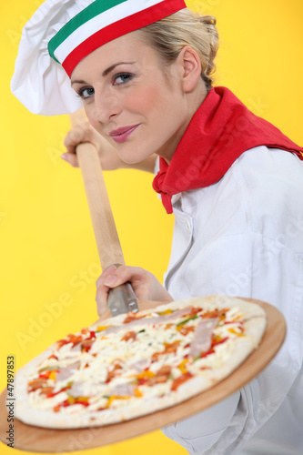 Photo: Woman putting pizza in oven Woman putting pizza in oven