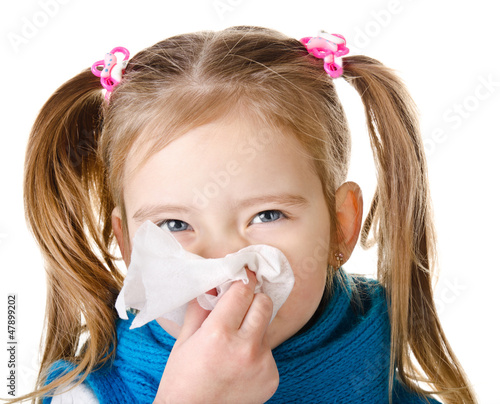 Photo: Little girl blowing her nose in a great effort closeup isolated Little girl blowing her nose in a great effort closeup isolated