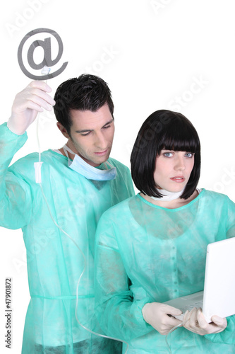 Photo: Surgeons with laptop and at symbol Surgeons with laptop and at symbol