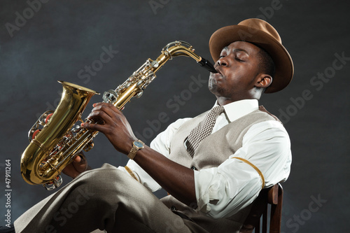Photo: Black american jazz saxophone player. Vintage. Studio shot. Black american jazz saxophone player. Vintage. Studio shot.