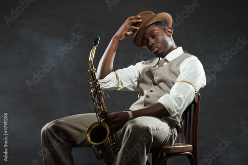 Photo: Black american jazz saxophone player. Vintage. Studio shot. Black american jazz saxophone player. Vintage. Studio shot.